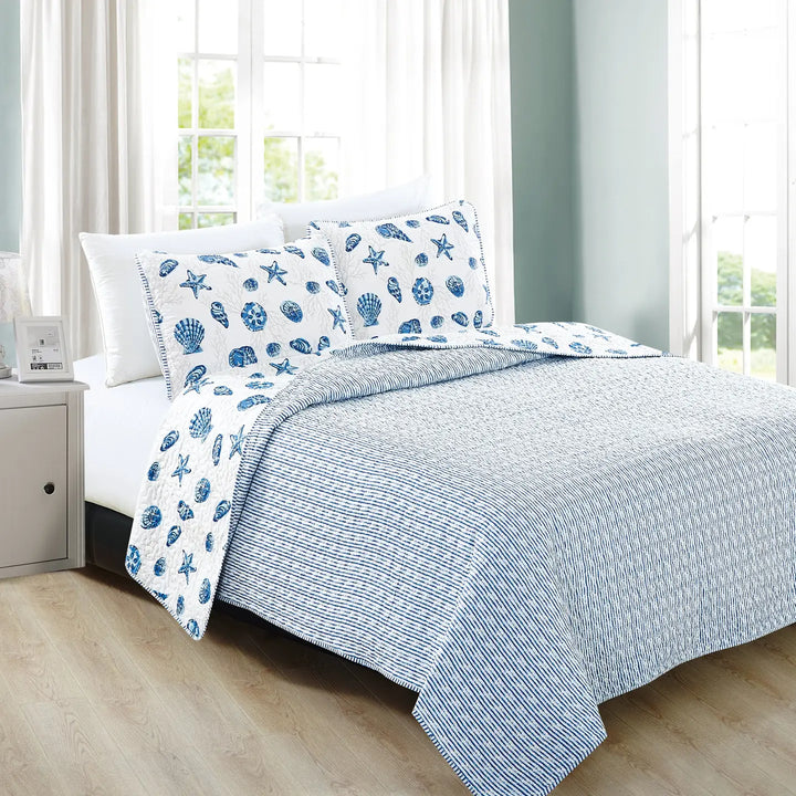 Bed with blue and white stripe patterned bedding in a bright bedroom