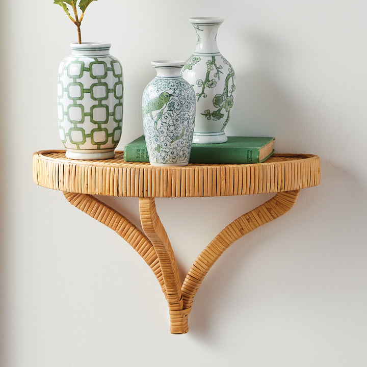 Wicker wall shelf with decorative vases and a book on a white wall. Coastal Compass Home Decor