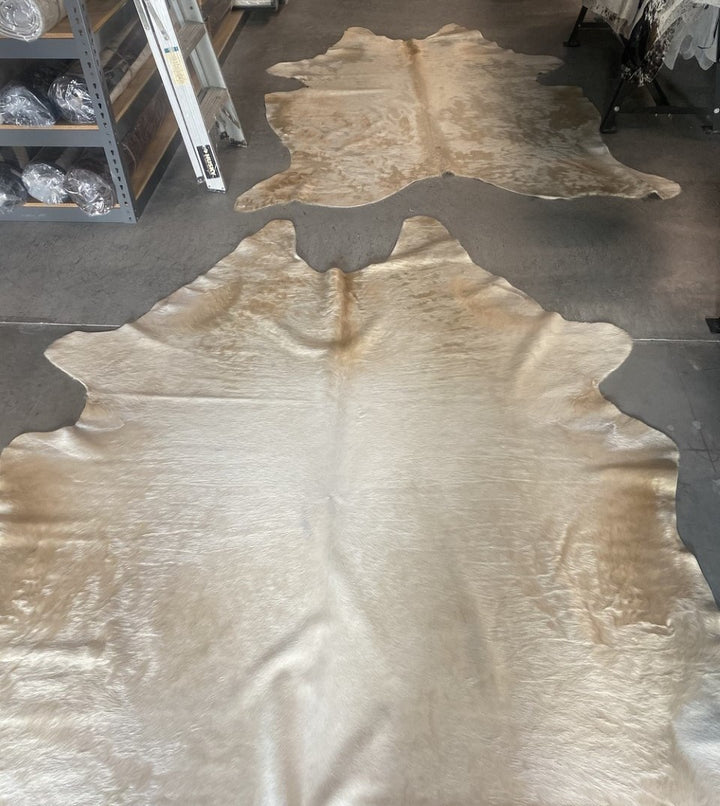 Champagne cowhide rugs in warehouse - The Coastal Compass Home Decor