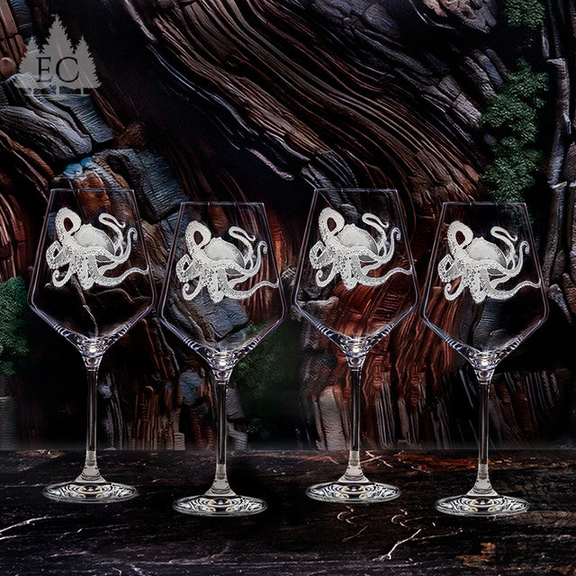 Four wine glasses with octopus engraved designs on a dark wooden background