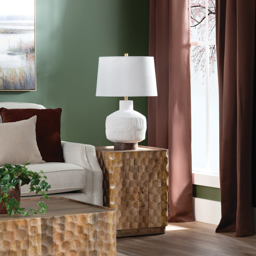 Alora Ceramic Table Lamp styled on a natural wood side table with green walls and living room space