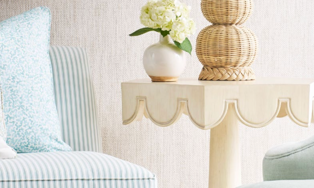 Decorative table with a vase of flowers and a lamp next to a striped chair. Coastal Compass Home Decor