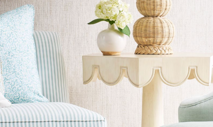 Decorative table with a vase of flowers and a lamp next to a striped chair. Coastal Compass Home Decor