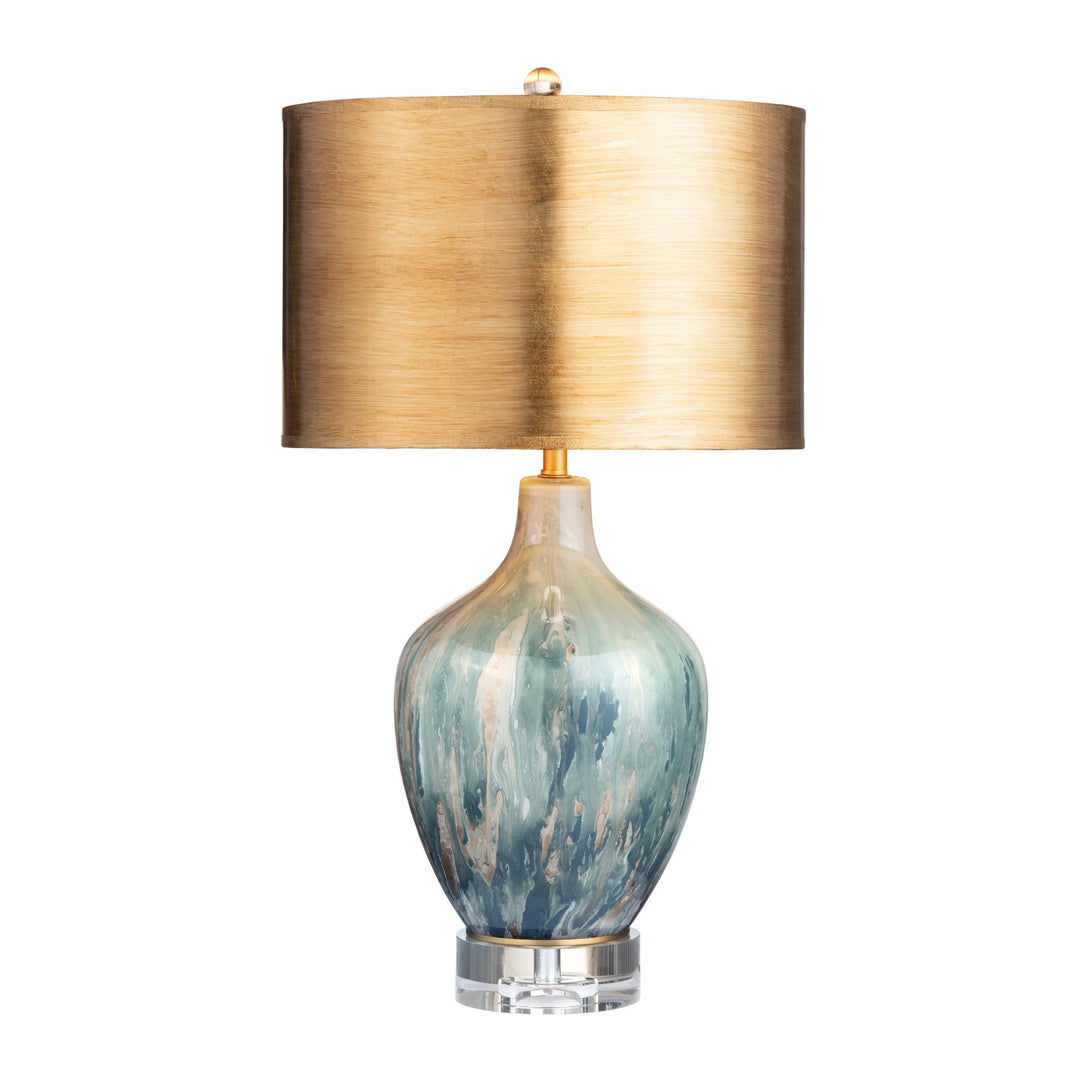 Aurelia Ocean Glass Lamp illuminated with warm gold shade and gold drum shade on white background