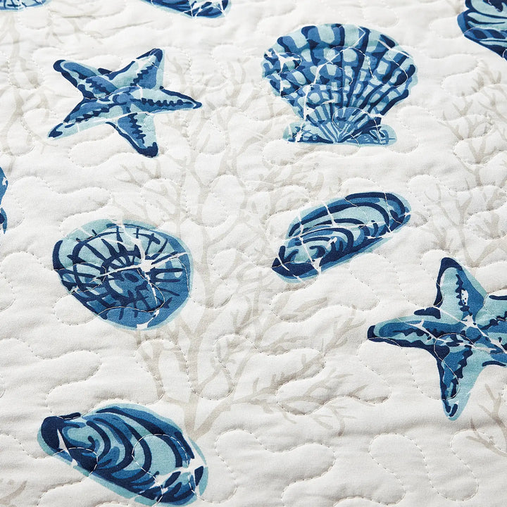 Quilt with blue starfish and shell patterns on a white