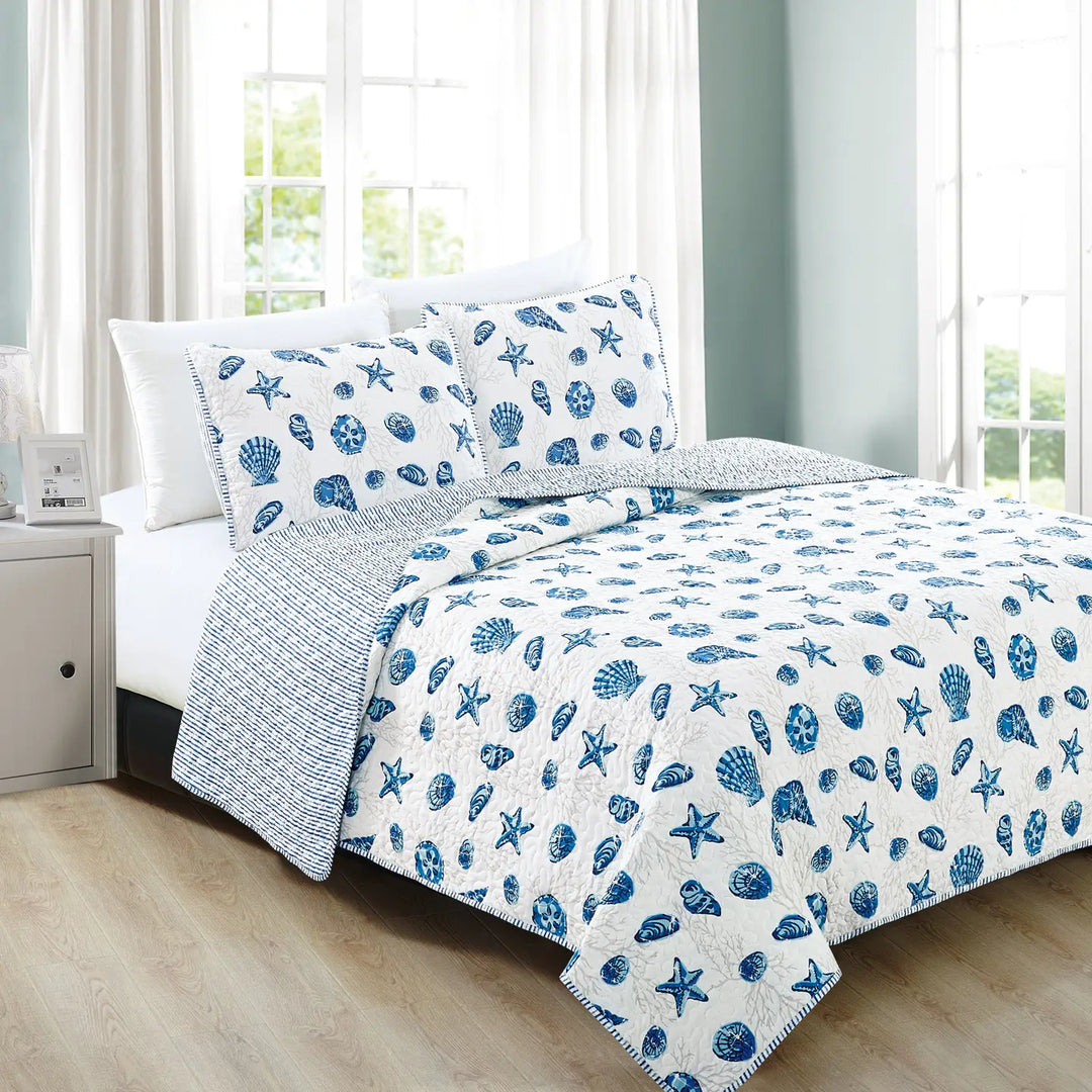 Bed with blue and white shell patterned bedding in a bright room.