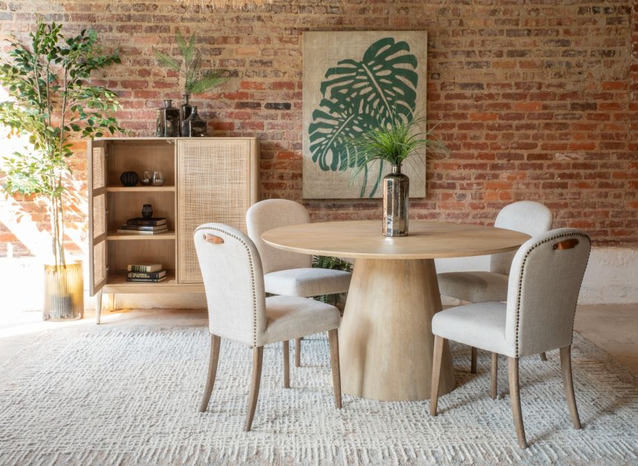 Blanco Mango Wood Round Dining Table with upholstered chairs and rattan cabinet with plant decor