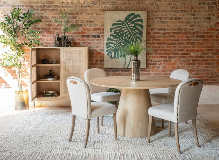 Blanco Mango Wood Round Dining Table with upholstered chairs and rattan cabinet with plant decor