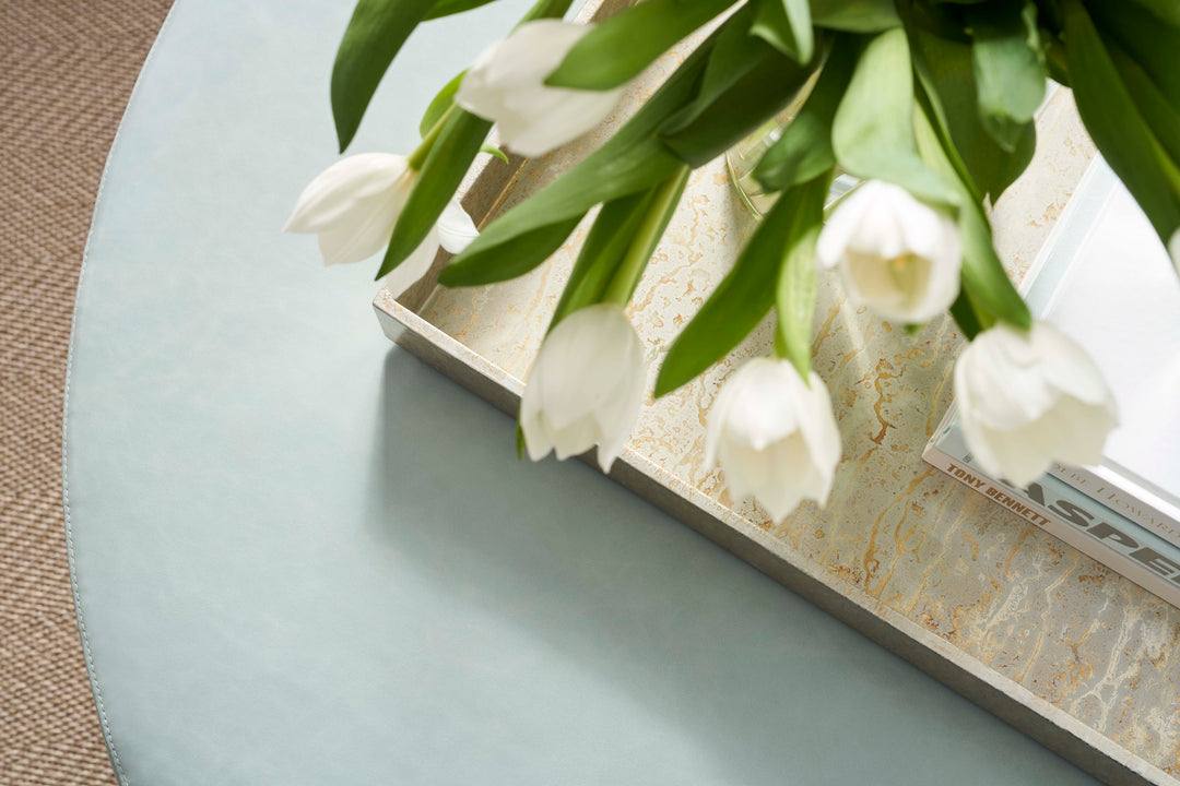 White tulips on a marble surface with a laptop in the background. Coastal Compass Home Decor
