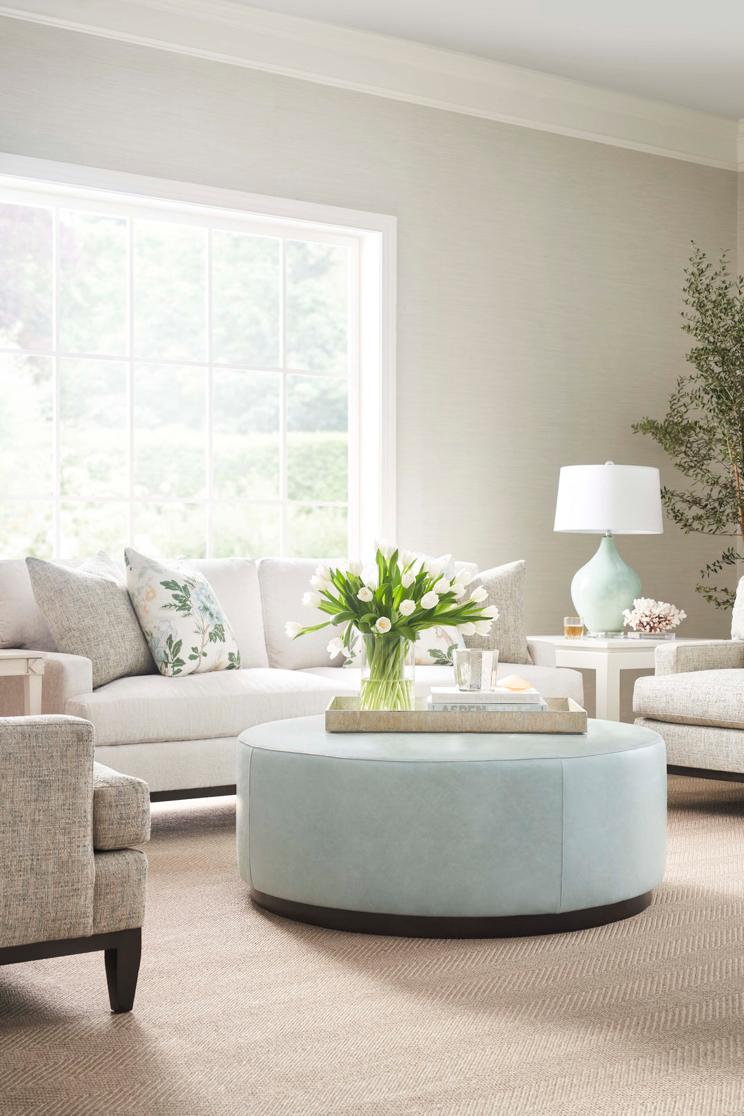 Modern living room with light gray sofa, round light blue coffee table, and decorative elements. Coastal Compass Home Decor