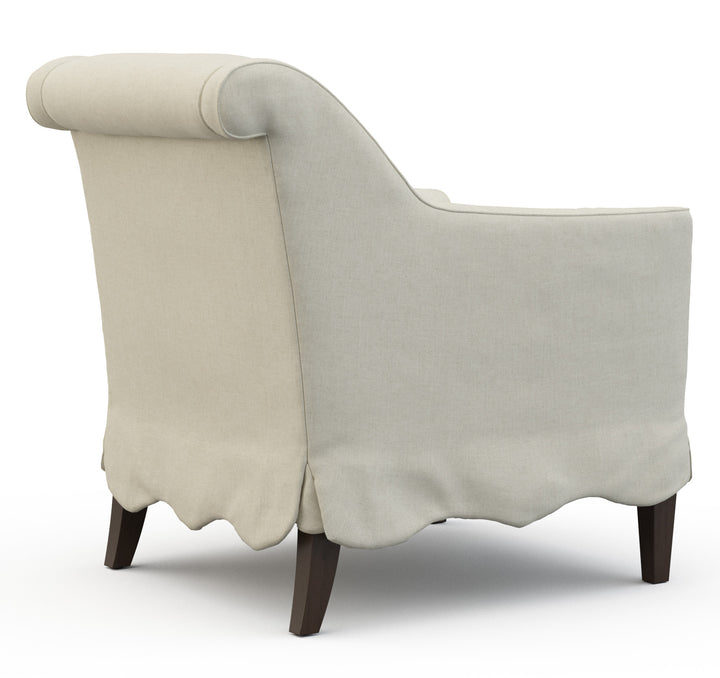 Beige armchair with scalloped skirt and wooden legs. Coastal Compass