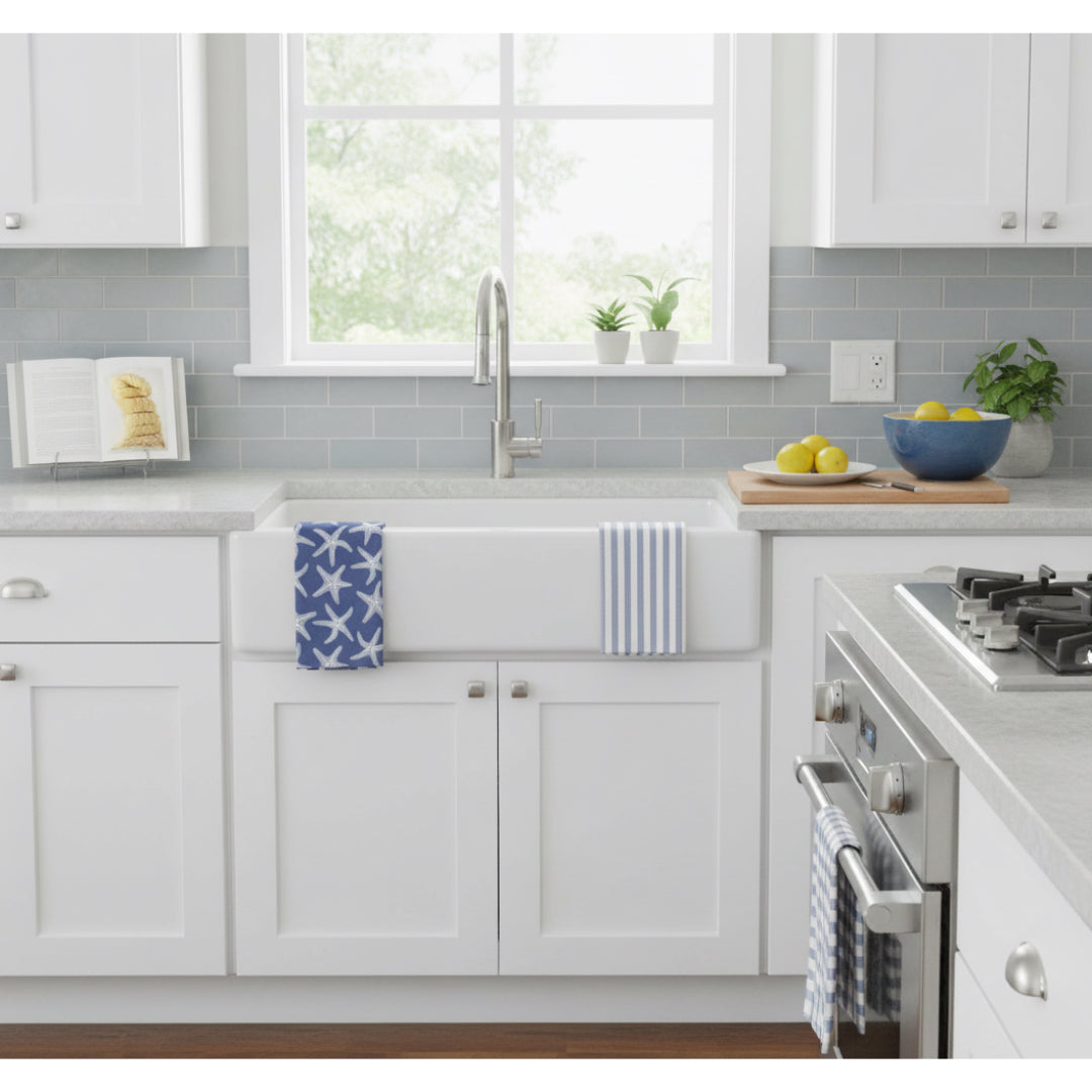 Modern kitchen with white cabinets, a starfish dishtowel and a blue and white stripe dishtowel on a sink