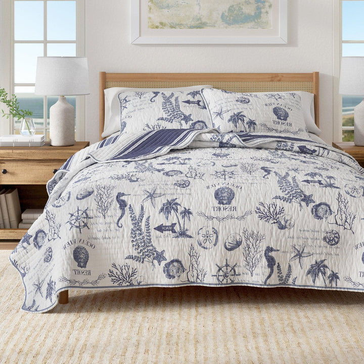 Calypso Quilt Set on Bed with nautical-motifs bedding in a bright room with windows and decor.