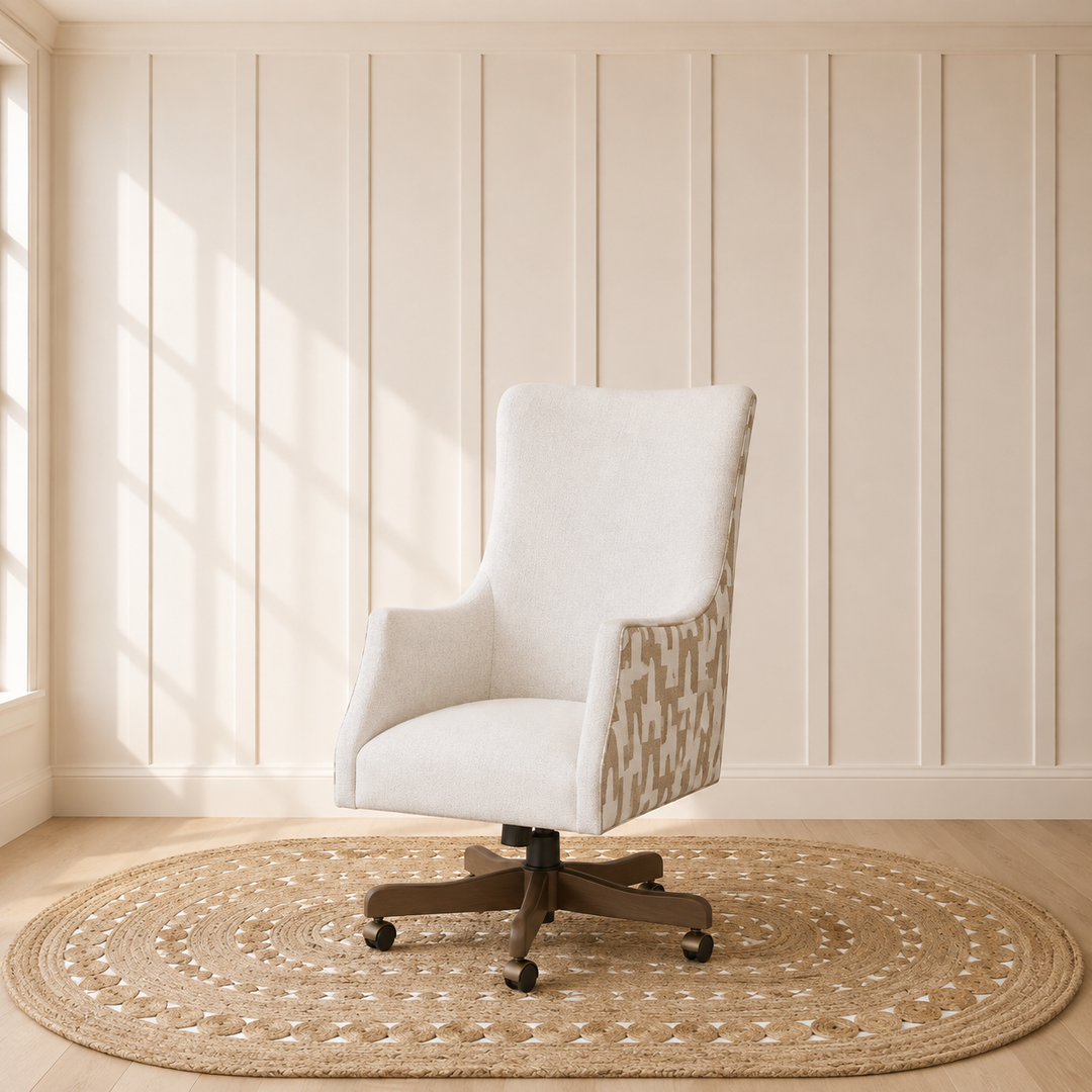 A modern swivel office chair with a light beige upholstered seat and back, patterned beige and white side panels, and a dark wood five-star base, set on a round woven jute rug in a room with cream paneled walls and a window.