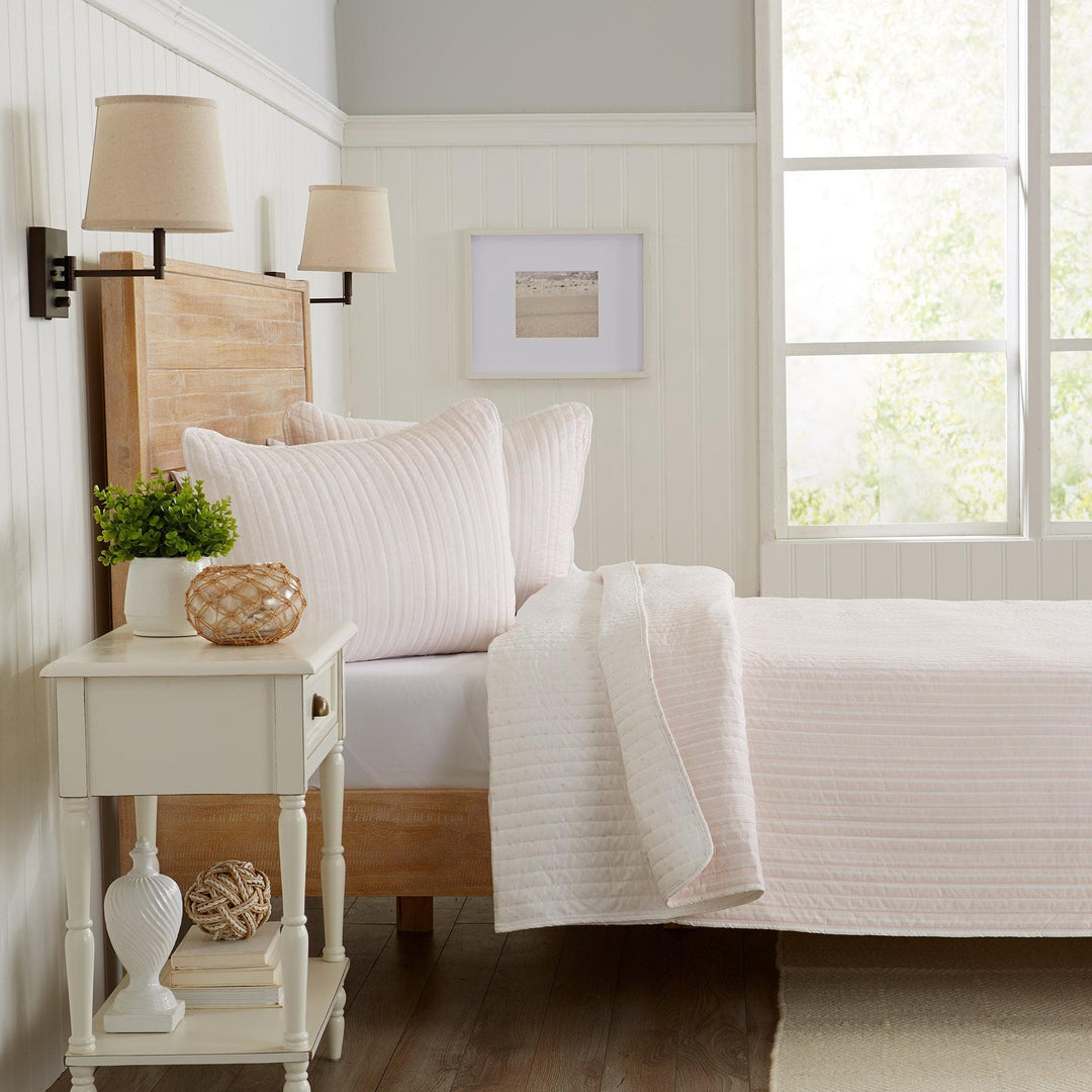 Bedroom with white bedding, wooden headboard, and side table with decorative items.