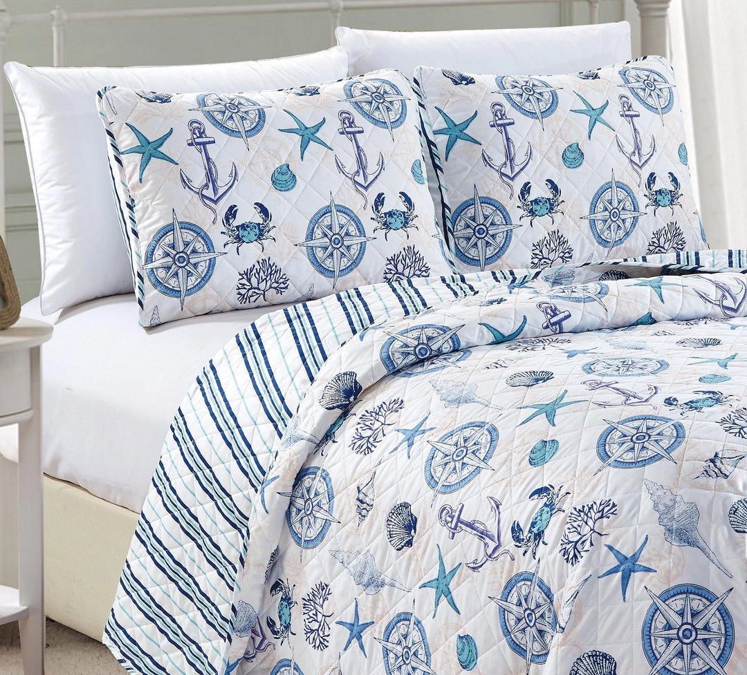 Nautical-themed bedding set with anchors, stars, and crabs on a bed.