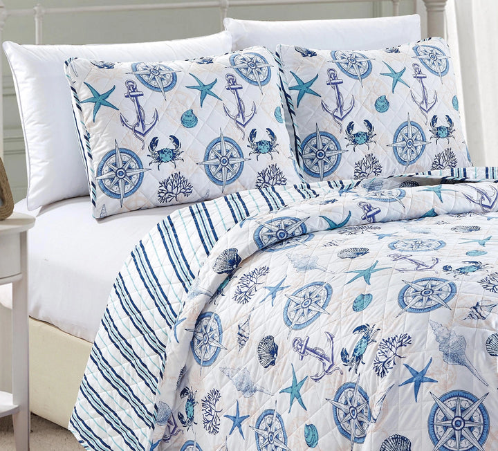 Nautical-themed bedding set with anchors, stars, and crabs on a bed.