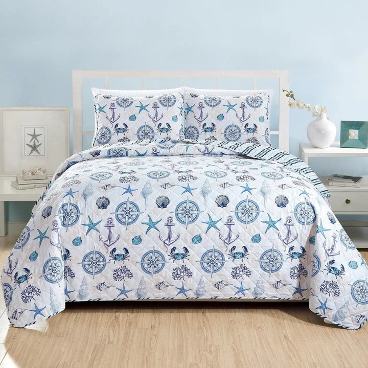 Nautical-themed bedding set on a bed with a light blue wall and wooden floor.