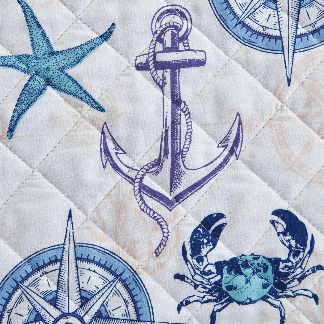Quilt with blue anchors, compasses, and crabs on a white background