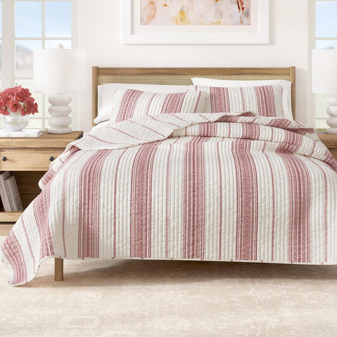 Red Striped bedding set on a bed in a bright bedroom with decor elements.