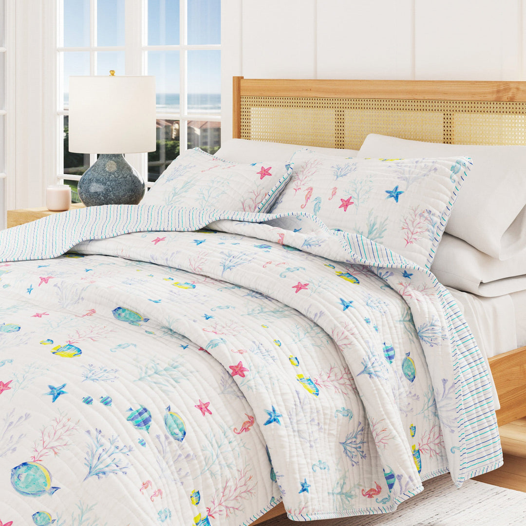Bed with colorful coastal quilt and pillows in a bright room