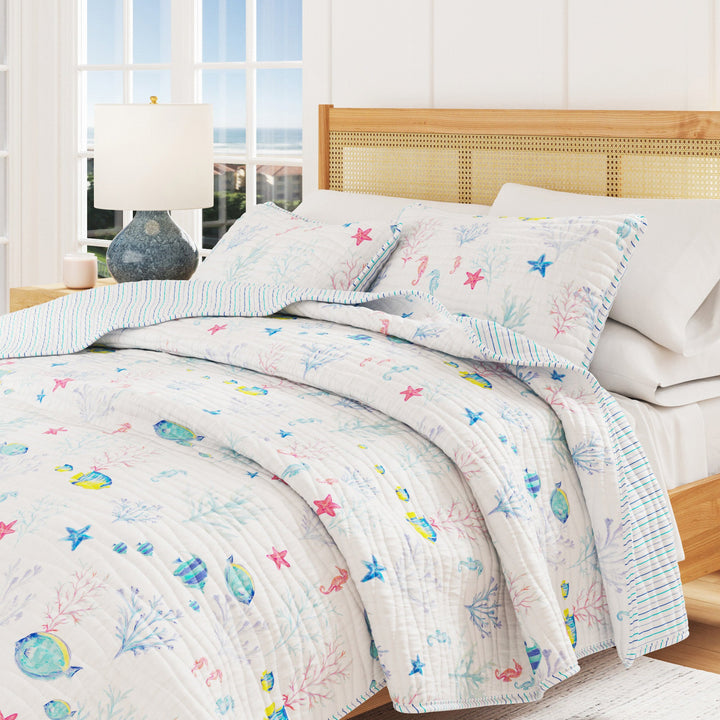 Bed with colorful coastal quilt and pillows in a bright room