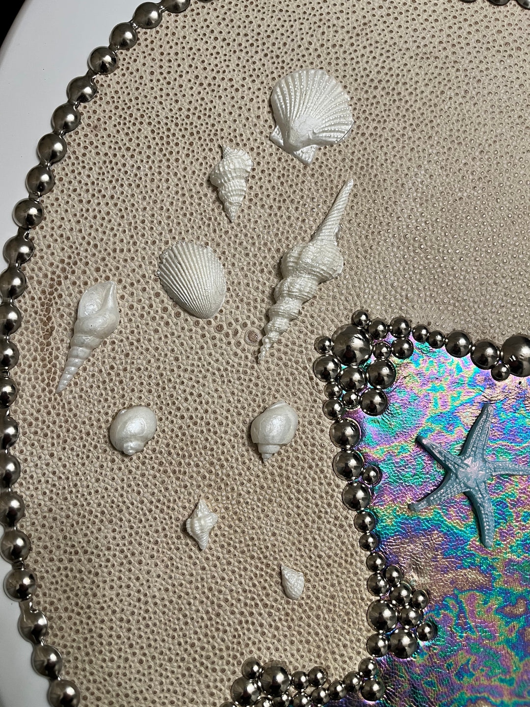 Decorative toilet seat coastal hoop with white shells and a colorful leather background