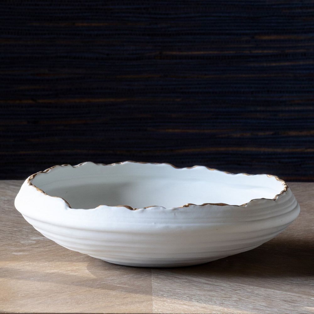 White ceramic bowl with gold rim on a wooden surface