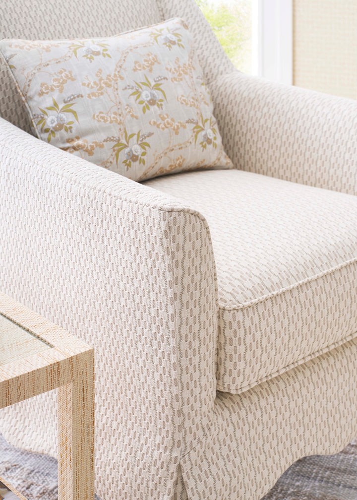 Beige armchair with a floral-patterned cushion in a bright room. Coastal Compass