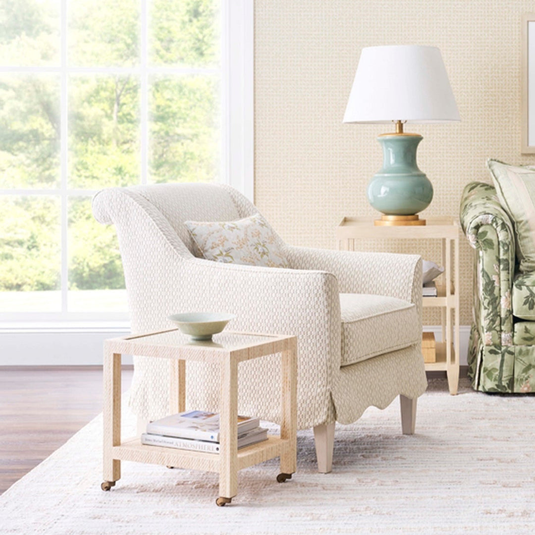 White armchair with a floral-patterned pillow in a bright living room. Coastal Compass Home Decor