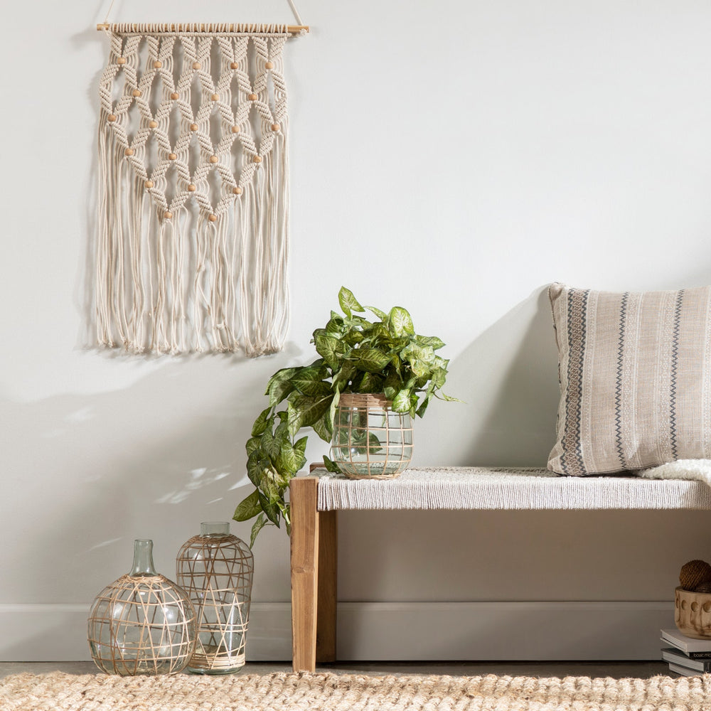 Living room with a woven wall art piece, plant, and textured rug.