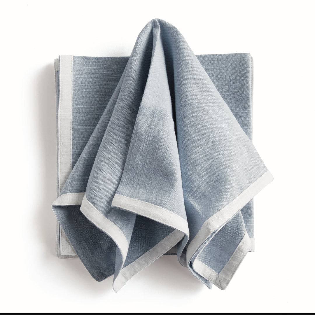Folded blue napkin with white boarder. Coastal Compass Home Decor