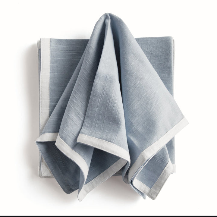 Folded blue napkin with white boarder. Coastal Compass Home Decor