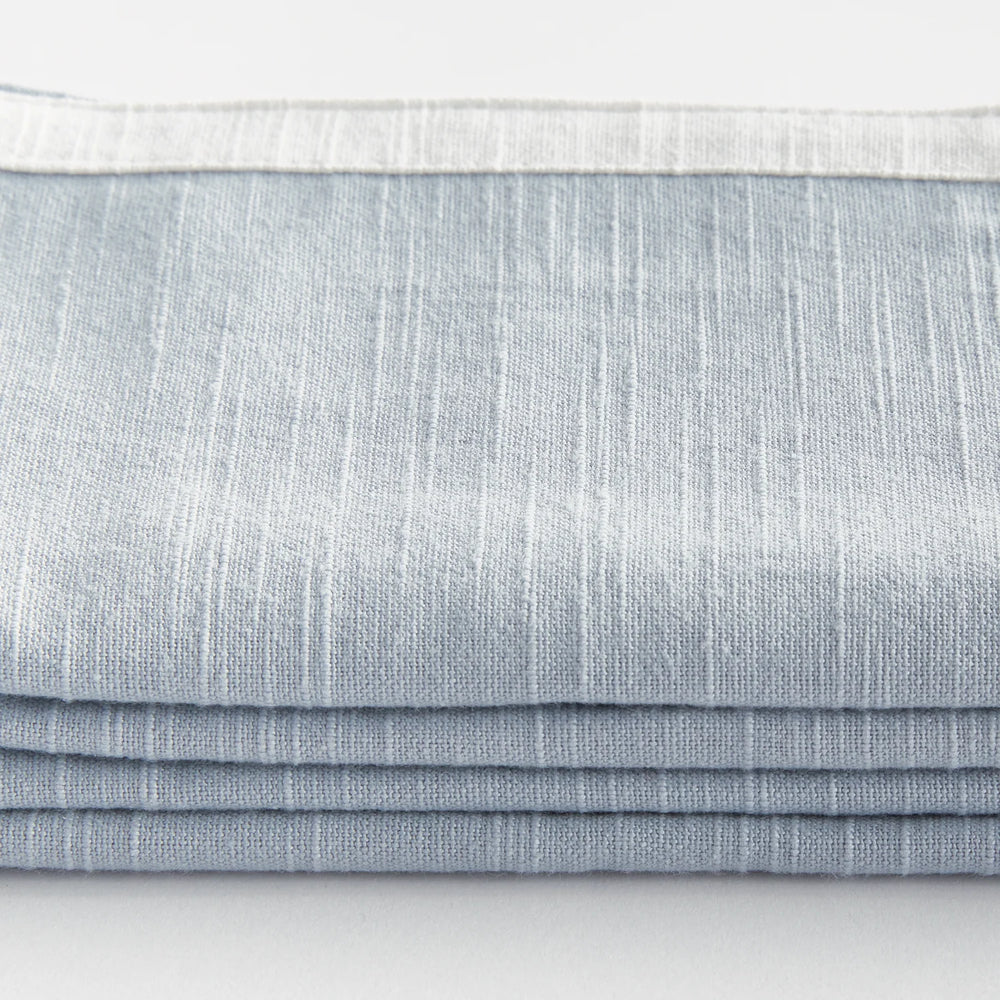 Stack of light blue napkins on a white background. Coastal Compass