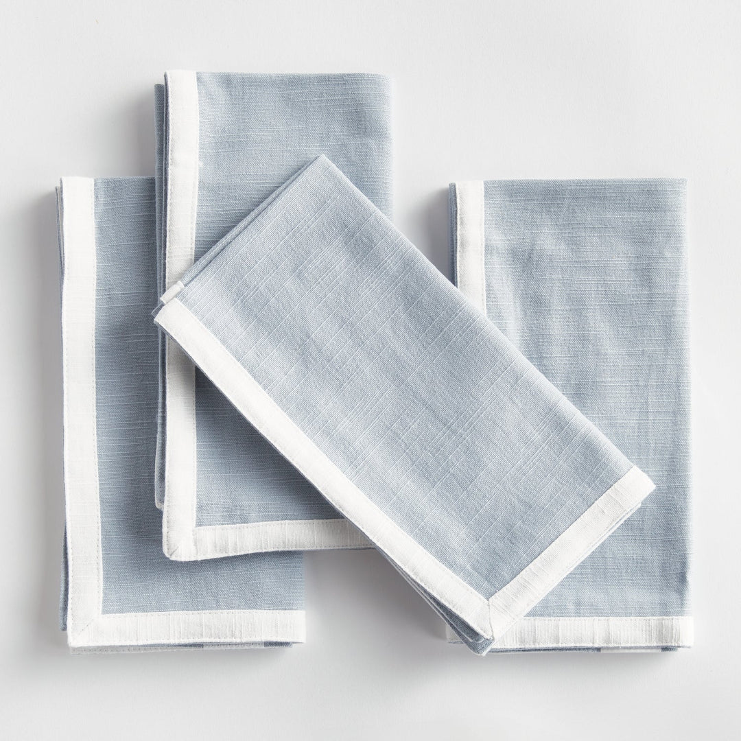 Set of light blue napkins with white borders on a white background. Coastal Compass
