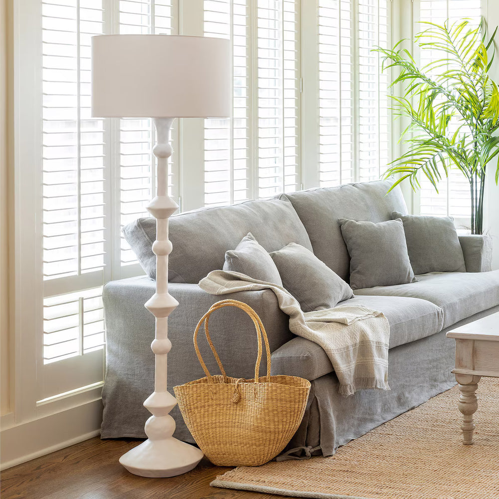 Living room with gray sofa, wicker basket, and white lamp.