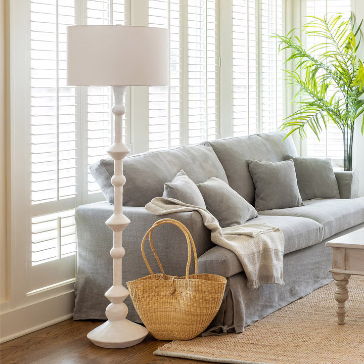 Living room with gray sofa, wicker basket, and white lamp.