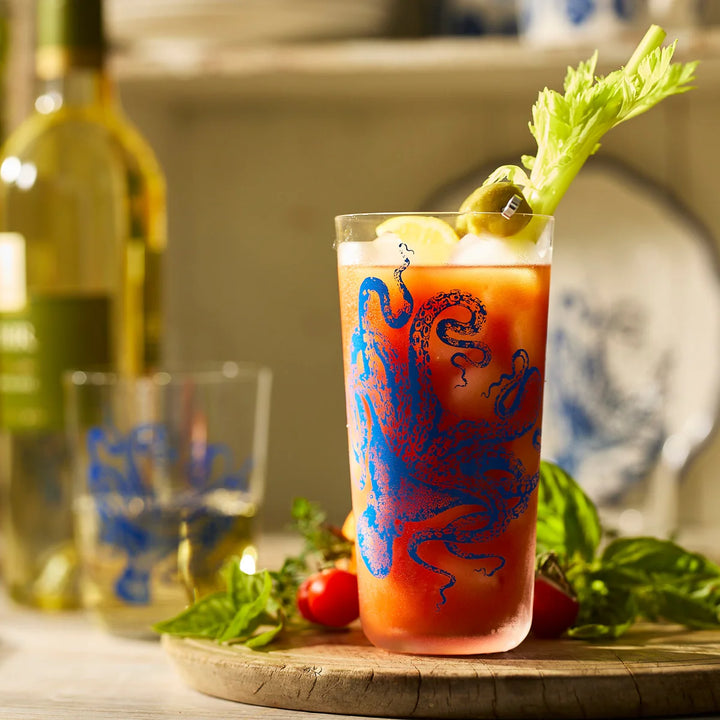  Bloody Mary cocktail with a dragon design on a wooden tray with a bottle of wine in the background.