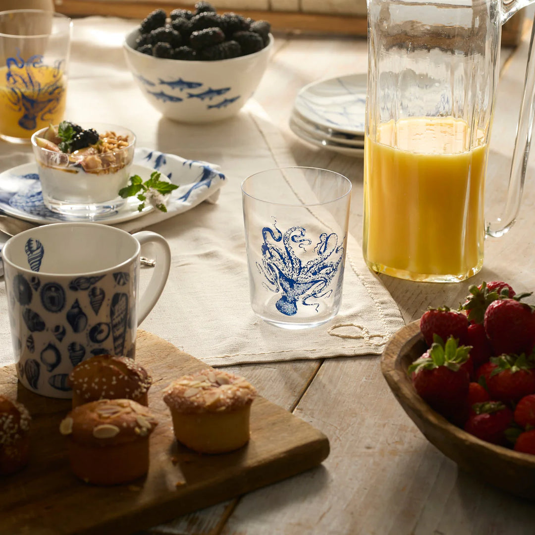 Breakfast table with mugs, fruit, and pastries on a wooden surface