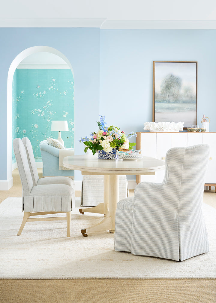 Dining room with white furniture, floral centerpiece, and light blue walls.