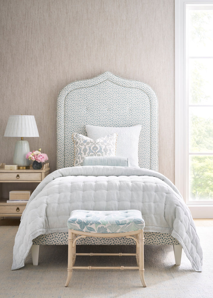 Bedroom with a bed featuring a patterned headboard and footstool with patterned fabrics.