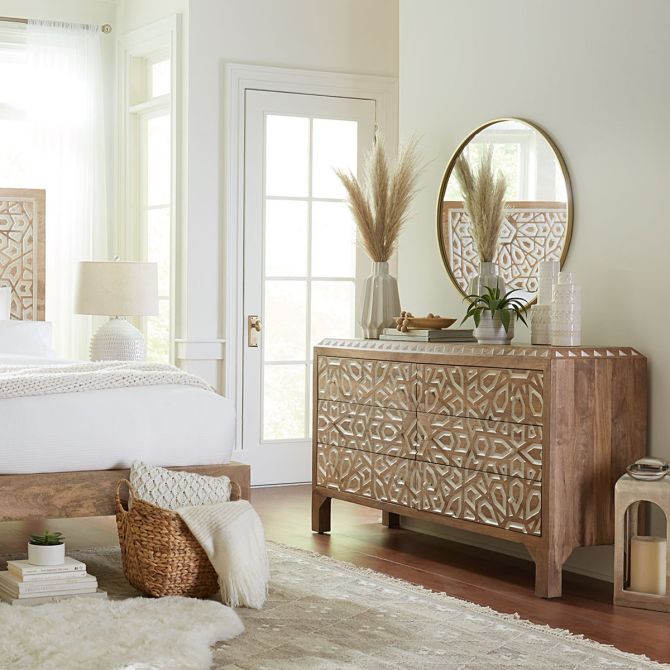 Mango wood hand carved dresser styled in coastal bedroom with carved bed, neutral decor, and light-filled spa