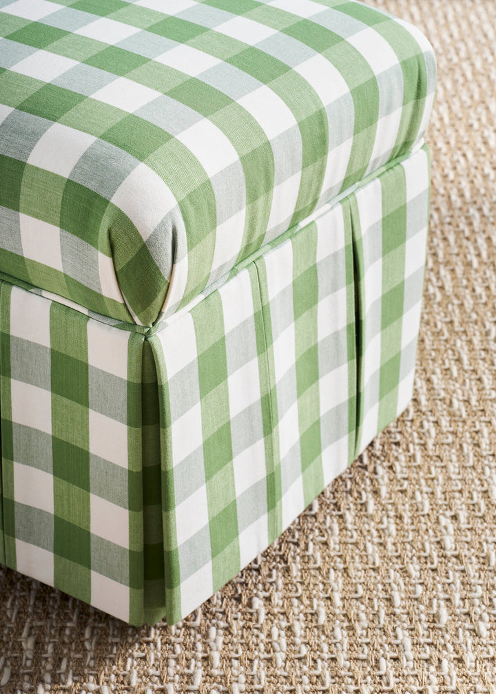 Green and white checkered ottoman on a textured carpet