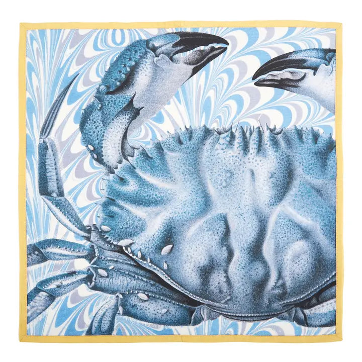 Coastal cotton dinner napkin featuring a blue crab illustration on a marbled blue background with yellow trim.