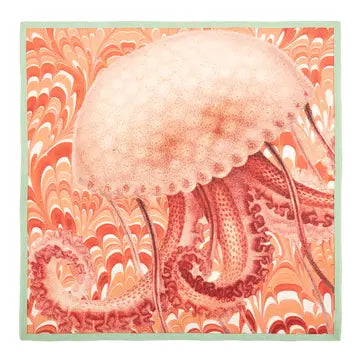 Coastal cotton dinner napkin featuring a soft coral jellyfish illustration on a marbled peach background with seafoam trim.