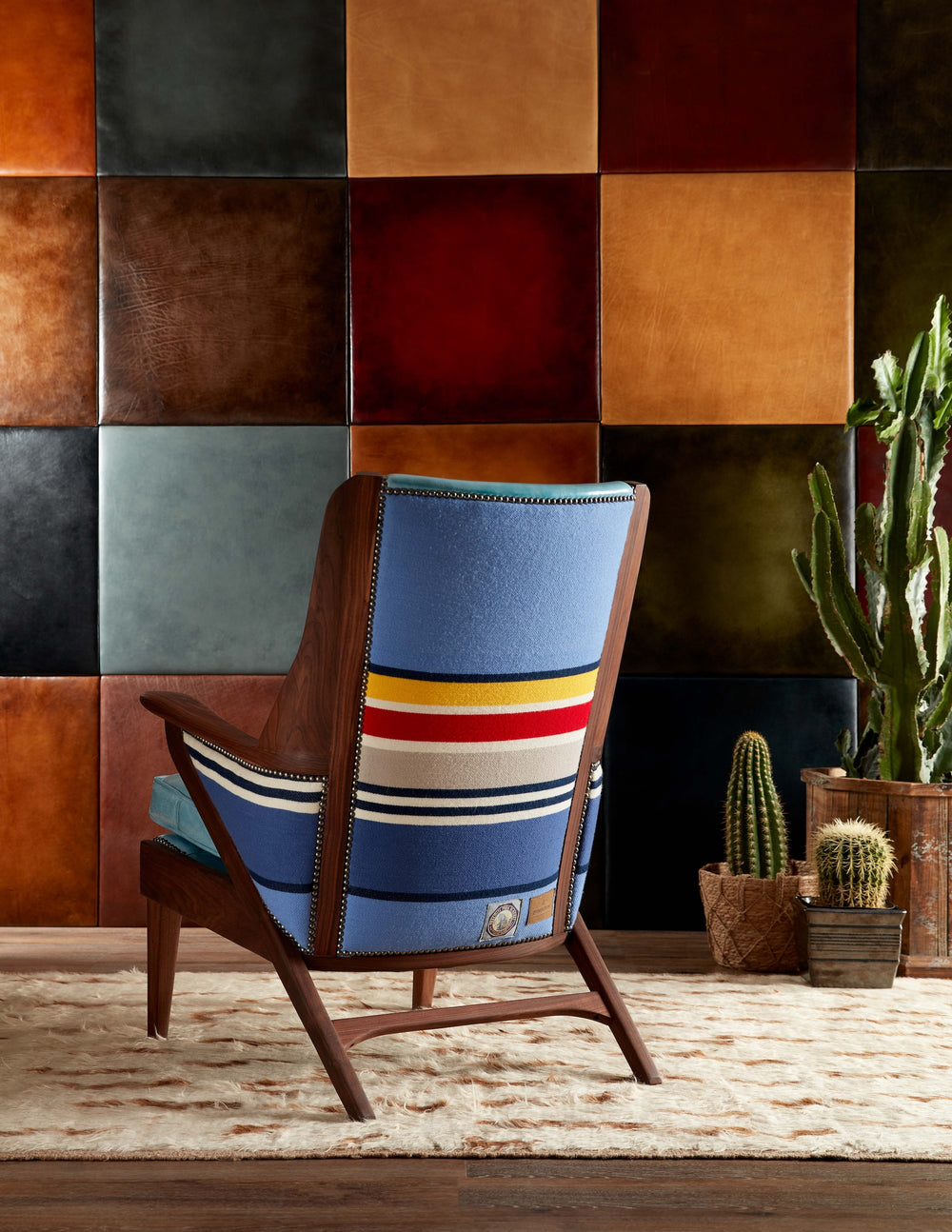 Chair with colorful backrest in front of a wall with square leather panels. Coastal Compass Home Decor