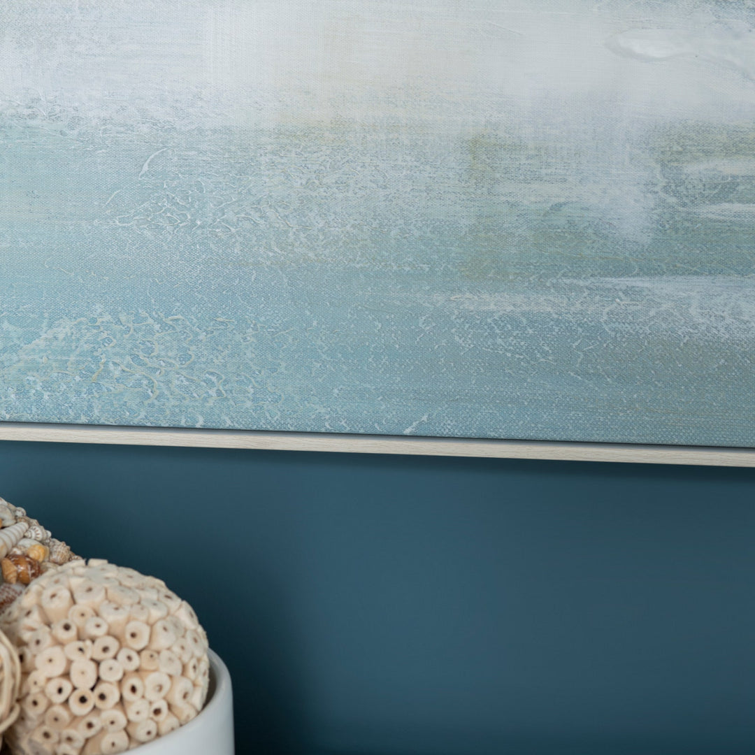 Close-up of a textured blue artwork with a white baseboard and a decorative shell on a dark blue wall.