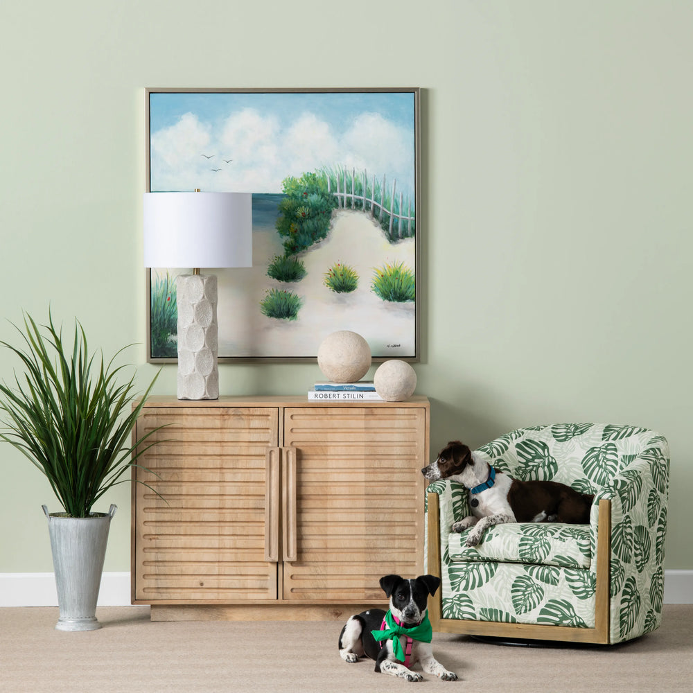 Port Baymouth 2-door cabinet styled in a coastal living room with beach artwork, table lamp, and greenery