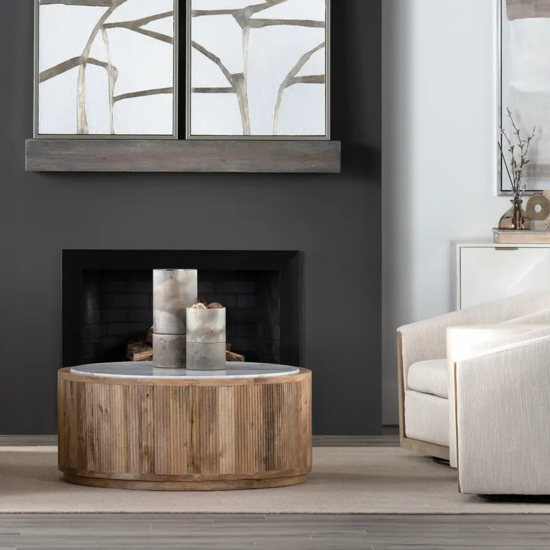 Modern living room with a round wooden coffee table, gray sofa, and abstract wall art.
