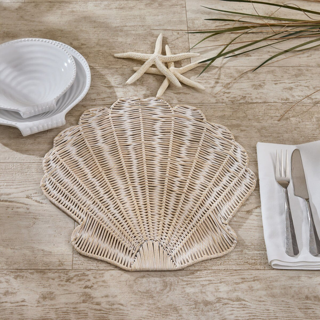 Shell-shaped placemat on a wooden table with starfish and cutlery.